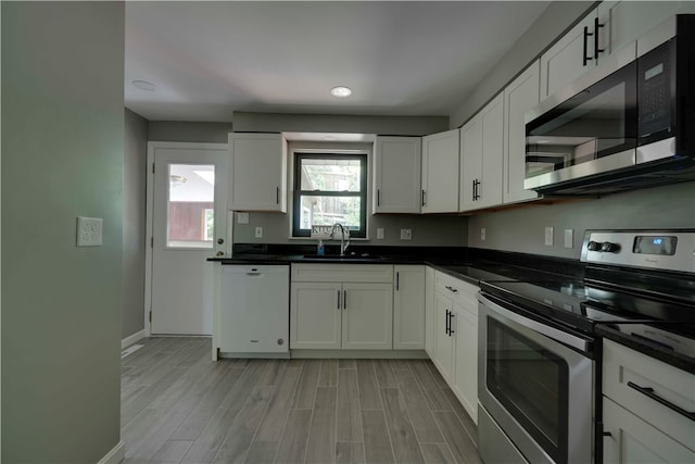 kitchen featuring appliances with stainless steel finishes, white cabinetry, sink, and light wood-type flooring