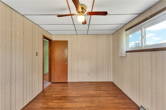 spare room with a drop ceiling, ceiling fan, and light wood-type flooring