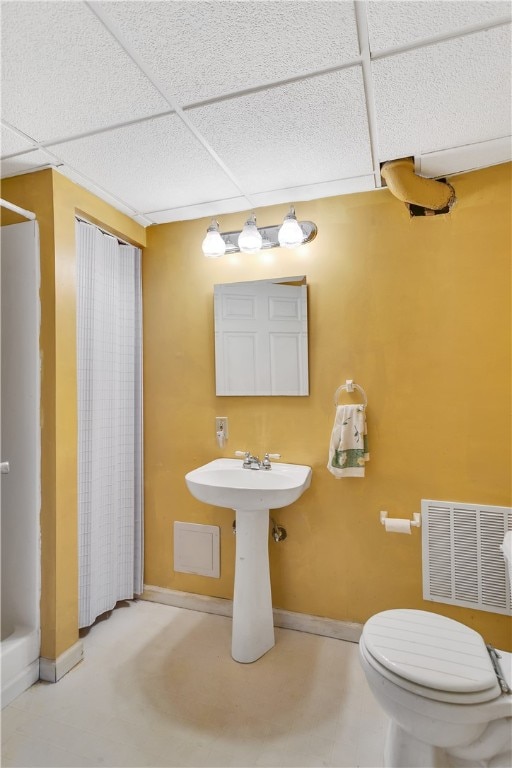 bathroom with a paneled ceiling and toilet