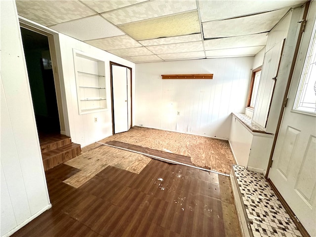 spare room featuring a paneled ceiling, wood walls, and dark hardwood / wood-style flooring