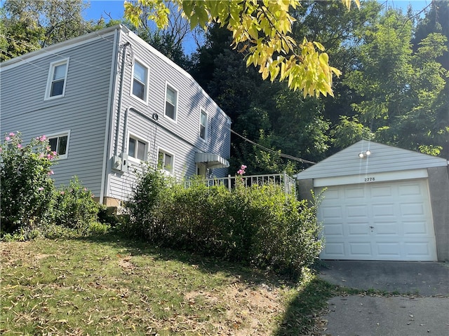 view of side of home featuring a garage, an outdoor structure, and a lawn