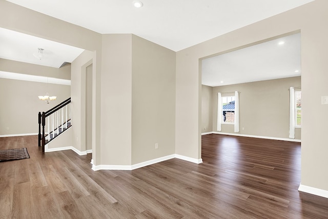 empty room featuring an inviting chandelier and wood-type flooring