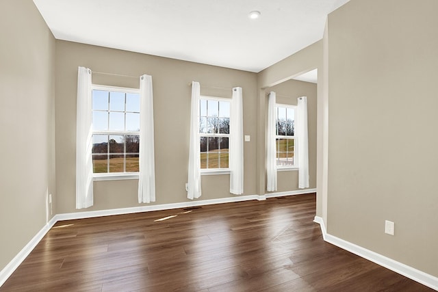 unfurnished room featuring plenty of natural light and dark hardwood / wood-style floors