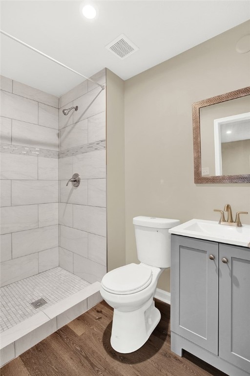 bathroom with vanity, toilet, wood-type flooring, and a tile shower