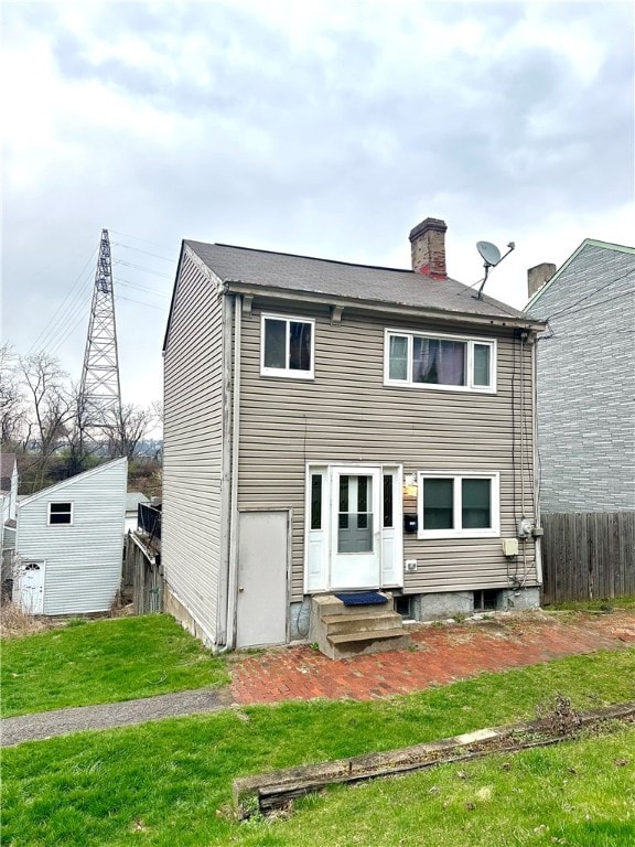 rear view of property with an outdoor structure and a yard