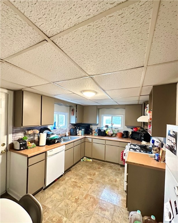 kitchen with range hood, white appliances, sink, a paneled ceiling, and light tile floors