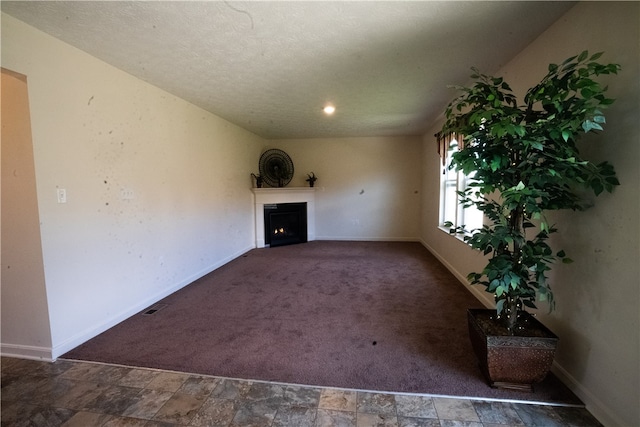 unfurnished living room featuring dark tile flooring and a textured ceiling