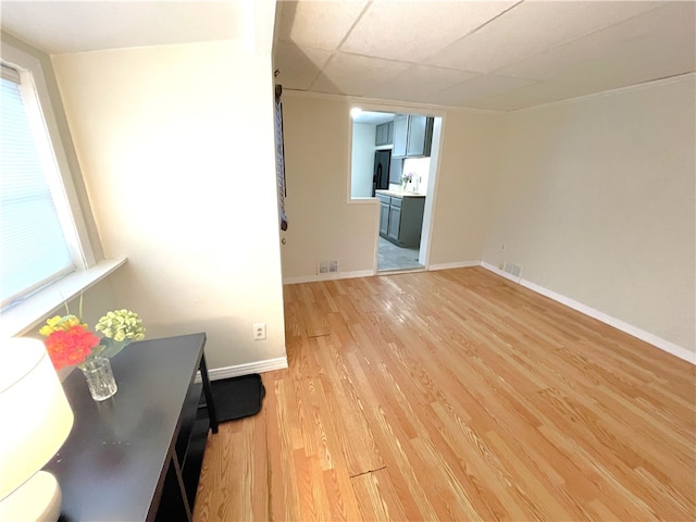 interior space featuring a drop ceiling and light wood-type flooring