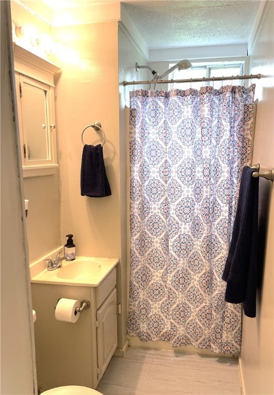 bathroom with crown molding, oversized vanity, toilet, and a textured ceiling