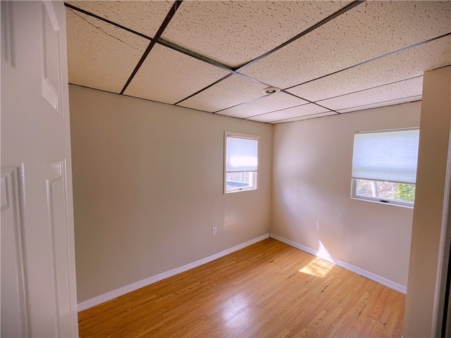 empty room with a paneled ceiling and light hardwood / wood-style flooring