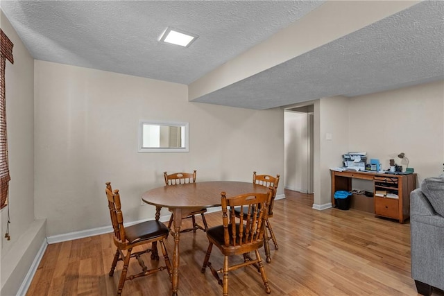 dining space with light hardwood / wood-style flooring and a textured ceiling