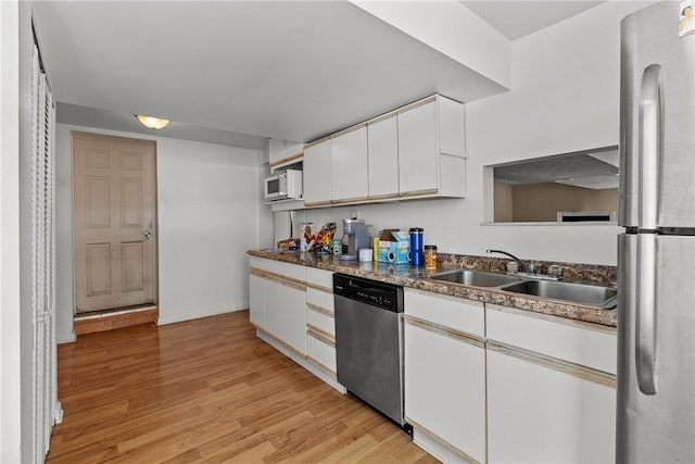 kitchen with stainless steel appliances, white cabinetry, sink, and light hardwood / wood-style flooring