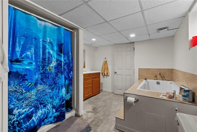 bathroom with vanity, a tub, and a paneled ceiling