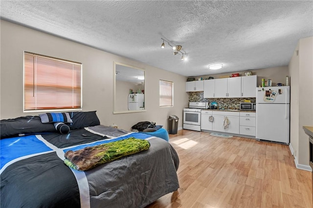 bedroom featuring sink, light hardwood / wood-style flooring, a textured ceiling, and white refrigerator