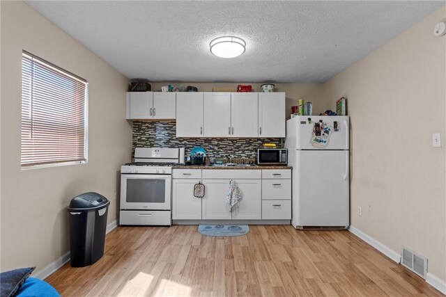 kitchen with white cabinetry, sink, white appliances, and tasteful backsplash