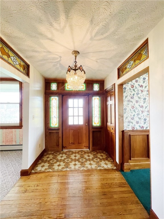 entrance foyer with light carpet, a textured ceiling, a chandelier, and a baseboard radiator