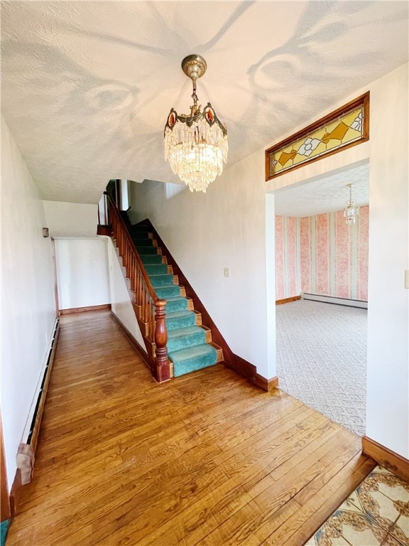 stairs featuring a chandelier, a textured ceiling, a baseboard radiator, and hardwood / wood-style flooring