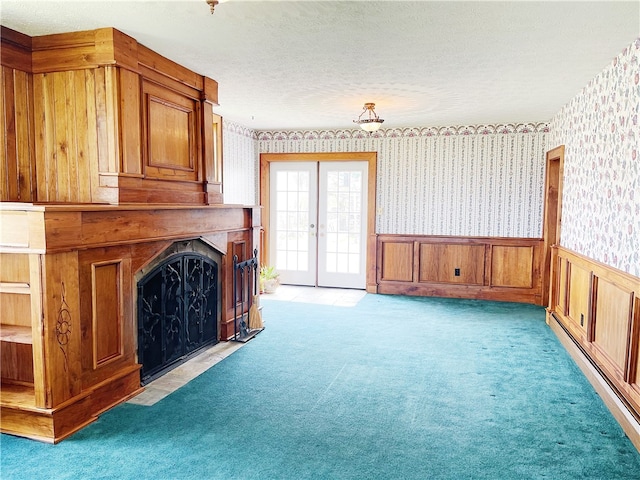 unfurnished living room featuring french doors, a textured ceiling, light colored carpet, and baseboard heating