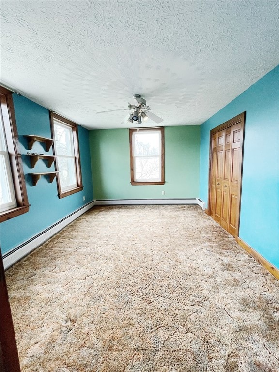 spare room with ceiling fan, baseboard heating, a textured ceiling, and carpet