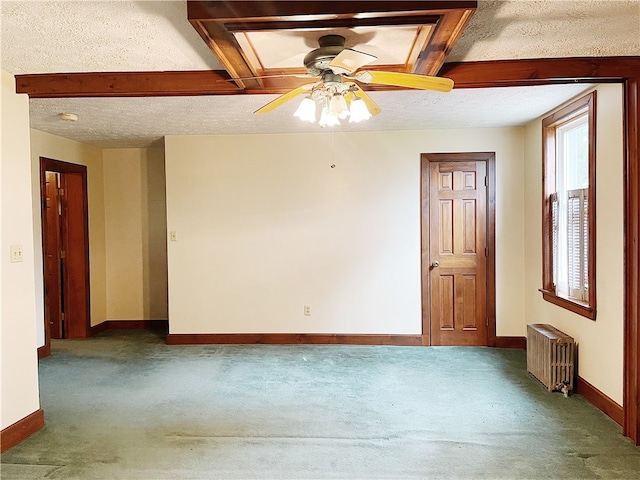 spare room with ceiling fan, a textured ceiling, dark colored carpet, and radiator heating unit