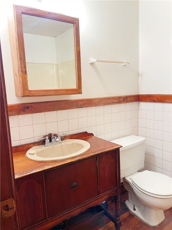 bathroom featuring tile walls, toilet, vanity, and wood-type flooring