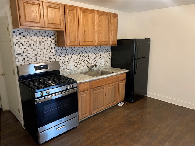 kitchen featuring black fridge, tasteful backsplash, stainless steel gas stove, dark wood-type flooring, and sink