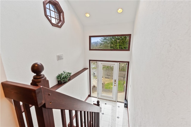 stairs featuring a healthy amount of sunlight, light tile patterned floors, and high vaulted ceiling