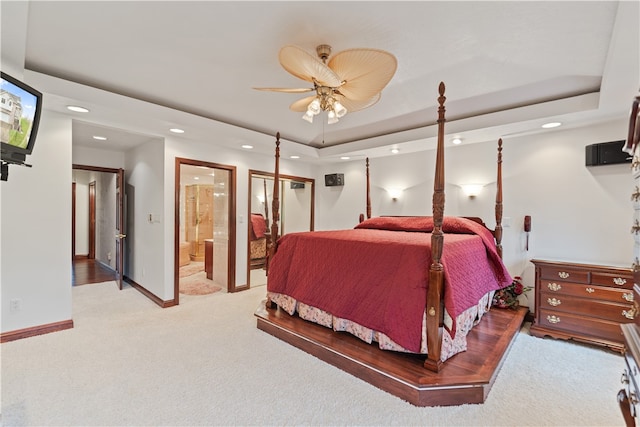 bedroom with light carpet, ceiling fan, and a tray ceiling