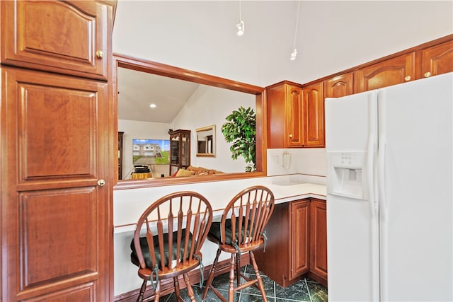 kitchen featuring vaulted ceiling, built in desk, white refrigerator with ice dispenser, and kitchen peninsula