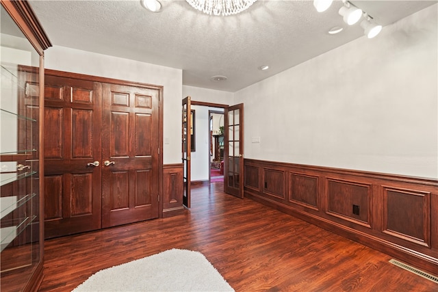 entryway featuring track lighting, a textured ceiling, and dark wood-type flooring