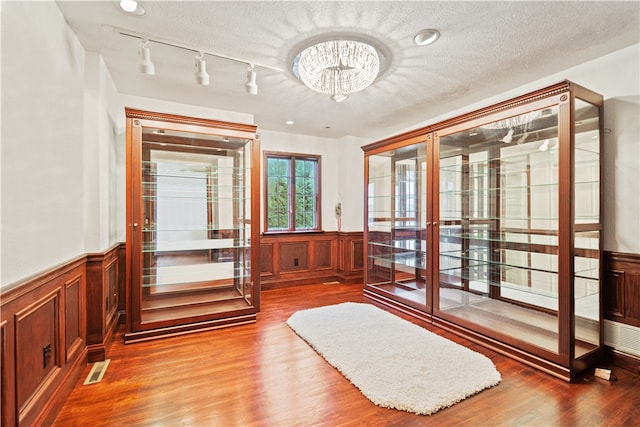 interior space with a textured ceiling, hardwood / wood-style floors, and track lighting