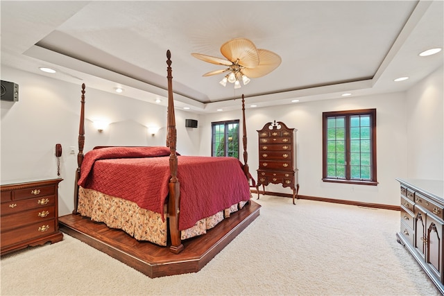 carpeted bedroom with ceiling fan and a raised ceiling