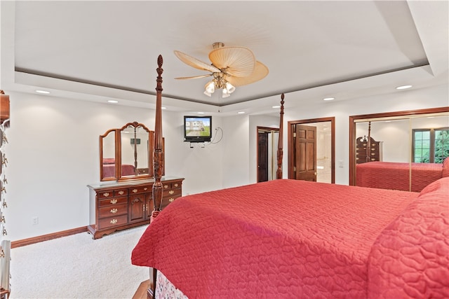 carpeted bedroom with ceiling fan and a raised ceiling