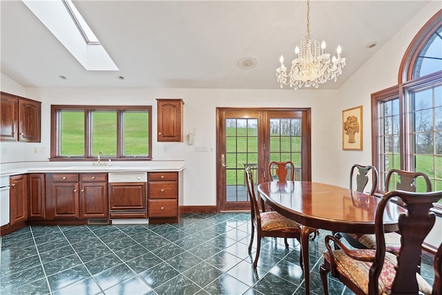 dining area with dark tile patterned floors, a healthy amount of sunlight, and vaulted ceiling with skylight