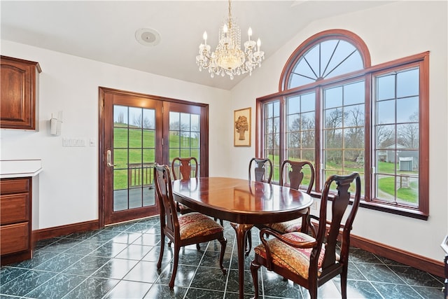 dining space with an inviting chandelier, dark tile patterned floors, lofted ceiling, and a healthy amount of sunlight