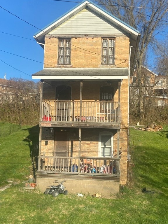 back of property featuring a balcony and a lawn