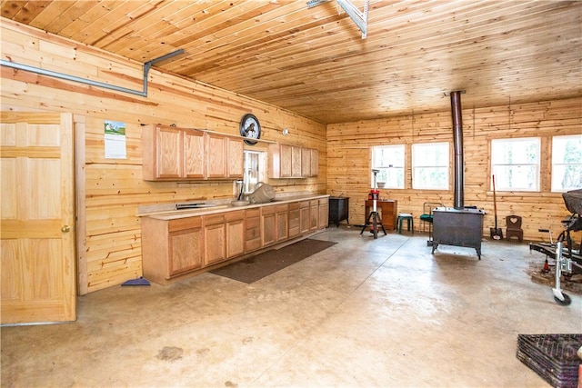 kitchen featuring light brown cabinets, wooden walls, wood ceiling, and a wood stove