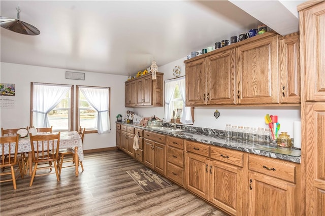 kitchen with sink, dark stone countertops, and hardwood / wood-style flooring