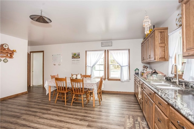 kitchen featuring dark hardwood / wood-style flooring, dark stone counters, and sink