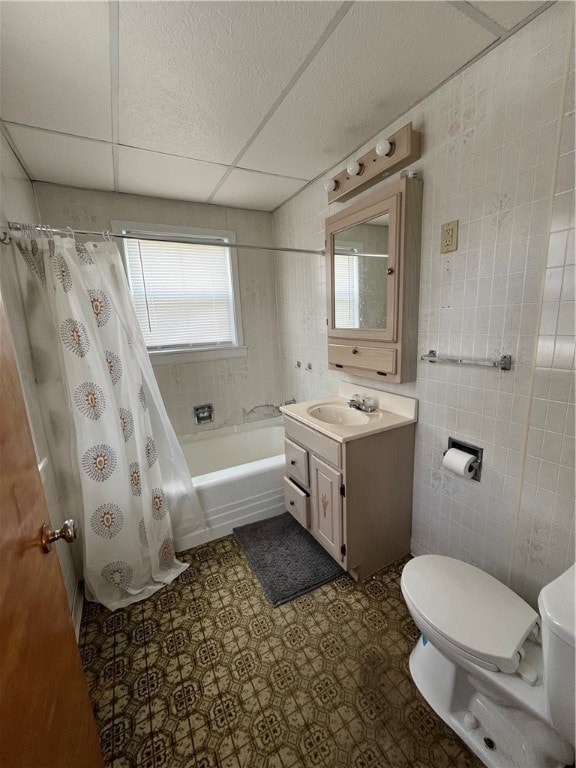 full bathroom featuring oversized vanity, toilet, shower / bath combination with curtain, a paneled ceiling, and tile walls