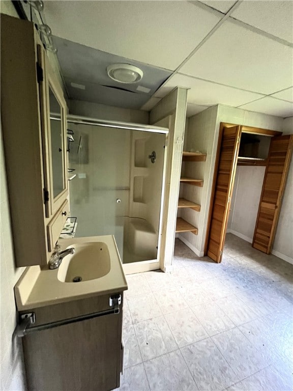 bathroom with tile floors, a paneled ceiling, an enclosed shower, and vanity