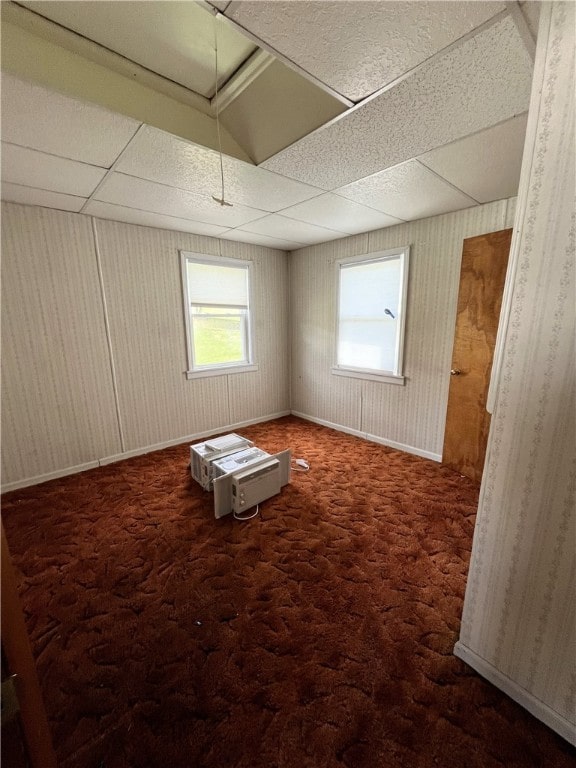 spare room featuring a paneled ceiling and dark carpet