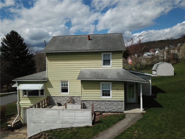 rear view of property with a storage shed and a lawn