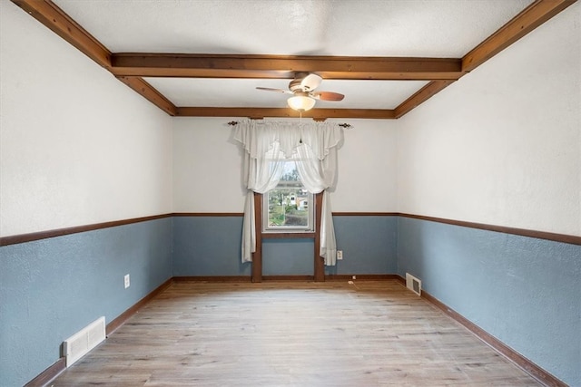 spare room with ceiling fan, a textured ceiling, light hardwood / wood-style flooring, and beamed ceiling