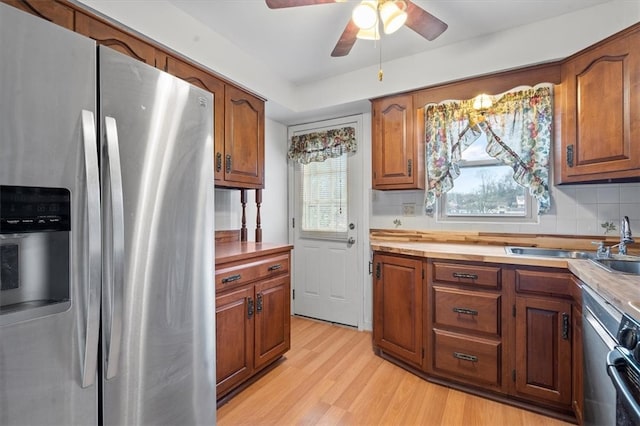 kitchen with light wood-type flooring, tasteful backsplash, ceiling fan, sink, and stainless steel refrigerator with ice dispenser