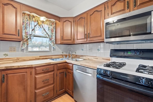 kitchen with backsplash, butcher block countertops, stainless steel appliances, and sink