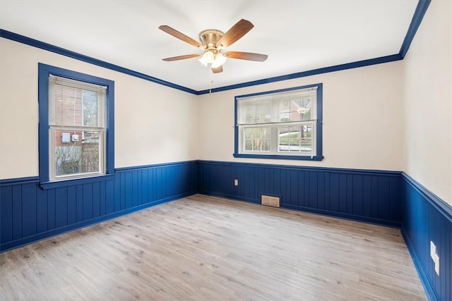 empty room with ceiling fan, light wood-type flooring, and ornamental molding