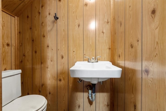 bathroom featuring toilet and wood walls