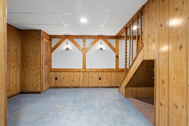 interior space with a paneled ceiling and wooden walls