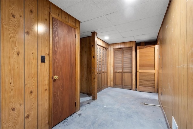 hall with a paneled ceiling and wooden walls